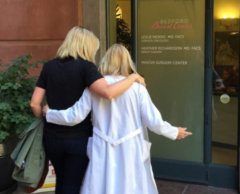 Two people walking towards the front door of the Bedford Breast Center