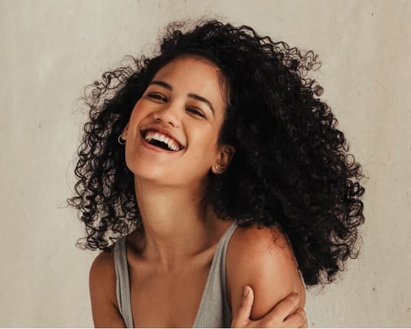 Woman with long curly black hair laughing