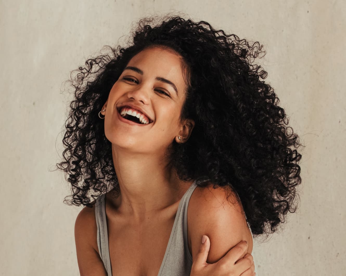 Woman with long curly black hair laughing