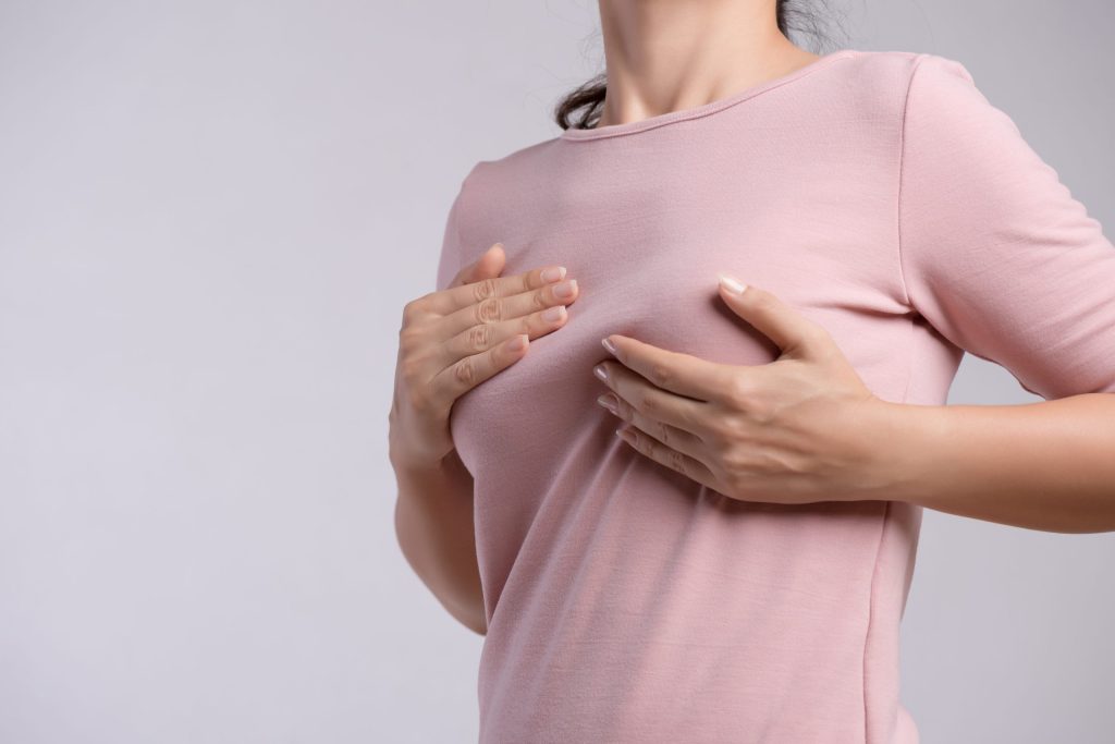 Woman hand checking lumps on her breast from fat injections.