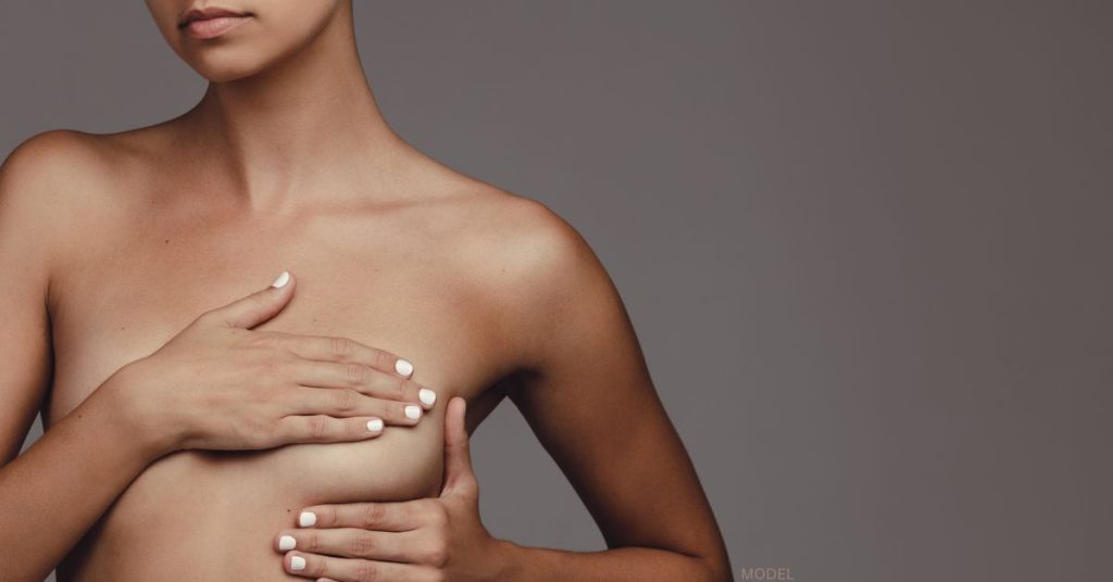 Woman holding her breast to represent breast cancer screening (model)