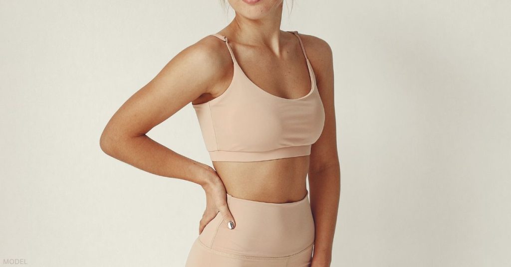 Woman's torso wearing a pink athletic sports bra and leggings (model)
