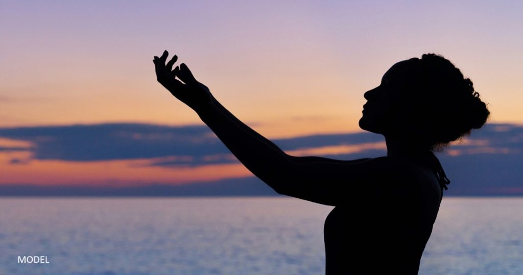 Woman promoting self-care standing on the beach