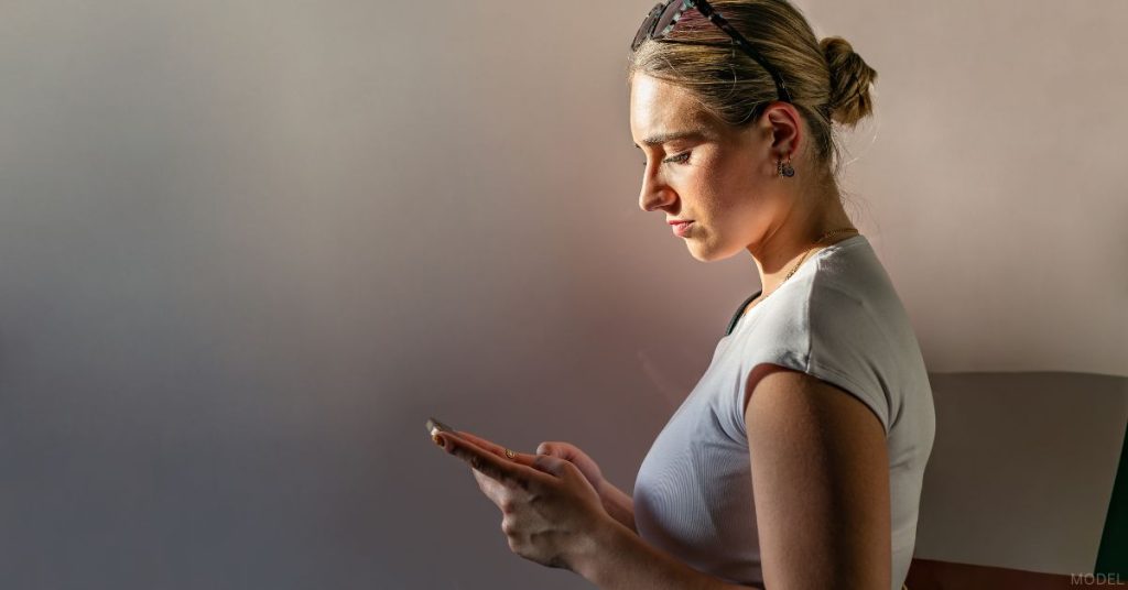 Woman looking pensively at her phone (model)